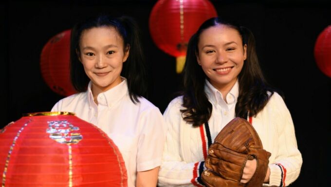 Two girls of Chinese ethnicity hold a lantern and a baseball mitt.