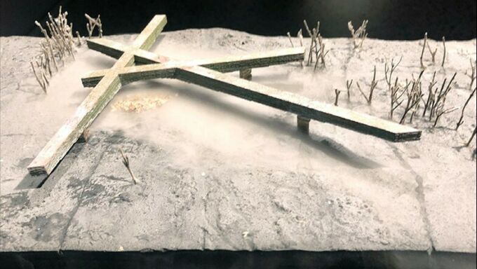 A close up of the Scorched Earth model with a cross on the ground and smoke rising from below