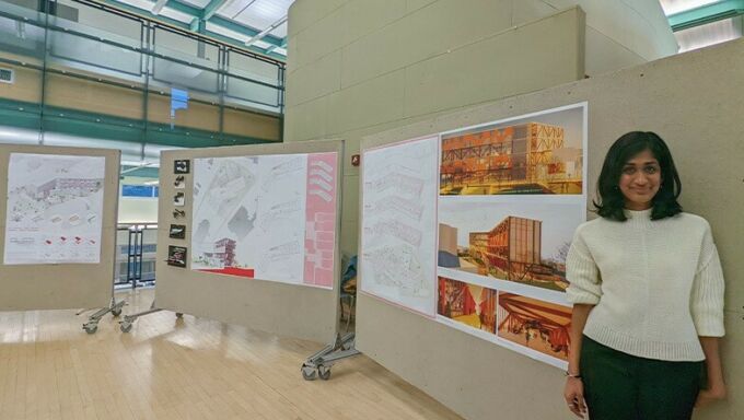 Anjali Gopalakrishnan stands next to pinup boards featuring her architectural renderings.