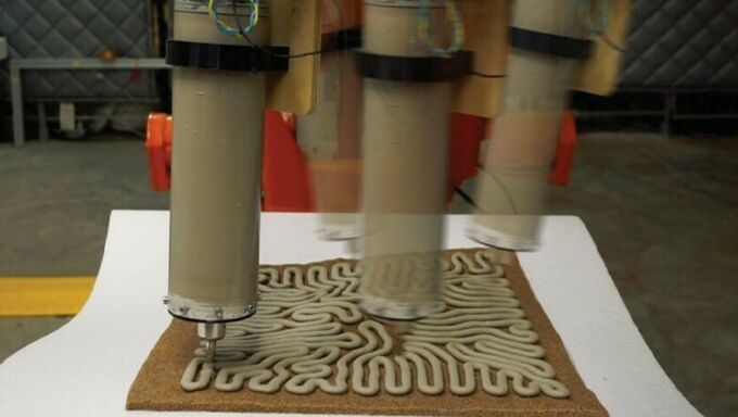 A time-lapse image showing a robotic arm extruding a concrete substance as it 3D prints a structure.
