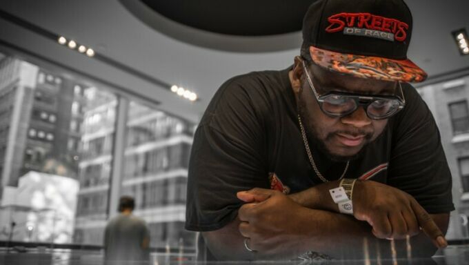 Penn State alumnus Raheem Jarbo, who performs as MegaRan, leaning on a reflective table.
