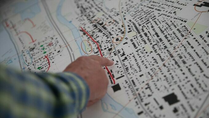 A close up photo of a man's hand pointing at a map showing housing clusters,