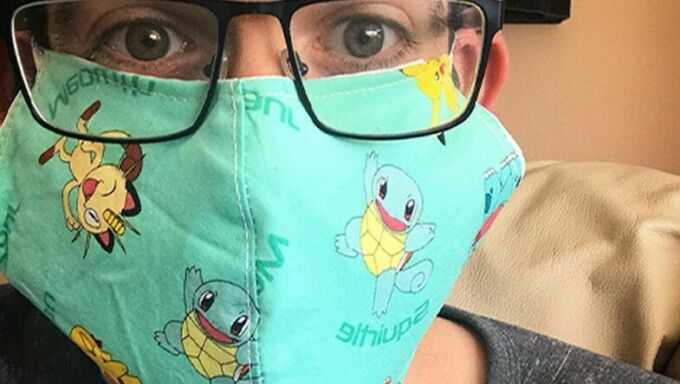 man with dark rimmed glasses posing with a Pokemon-themed mask