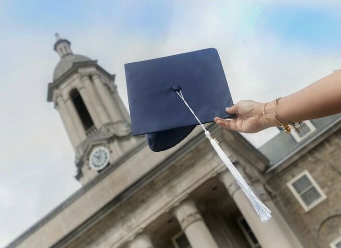 A mortarboard held up in front of Old Main