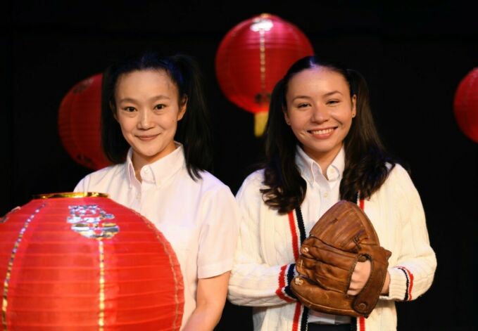 Two girls of Chinese ethnicity hold a lantern and a baseball mitt.