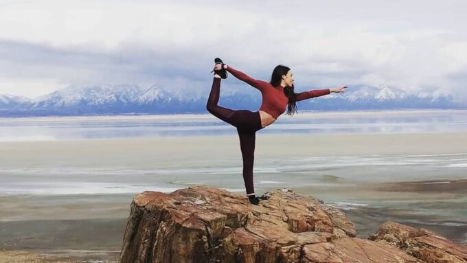 Lauren Schoth performing yoga on a rock with mountains in the background