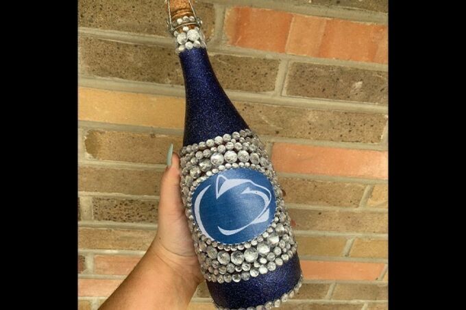 Dark blue painted champagne bottle with Penn State logo bedazzled