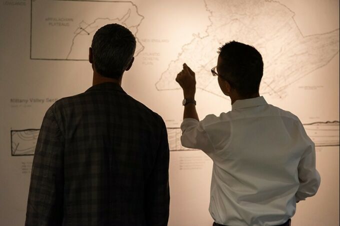 The backs of two people looking at the topographic map of the region.