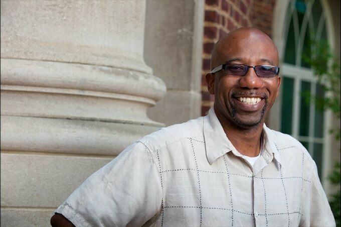 Bald Black man with dark glasses and a goatee smiling