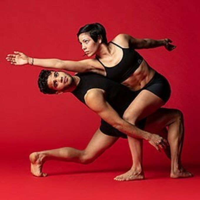 Once dancer lunges and leans back while a second dancer straddles his leg.