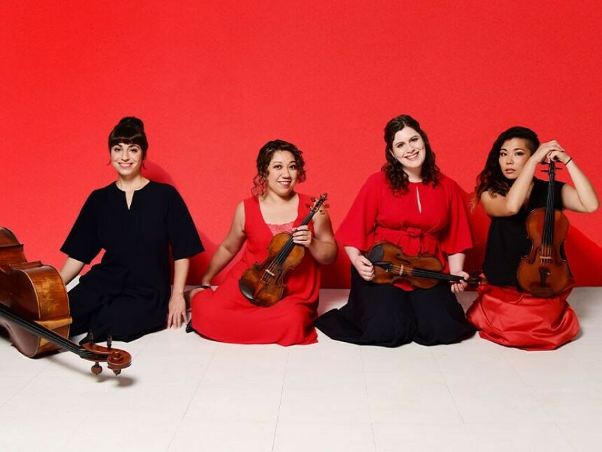 Four women sit in a row with their stringed instruments.