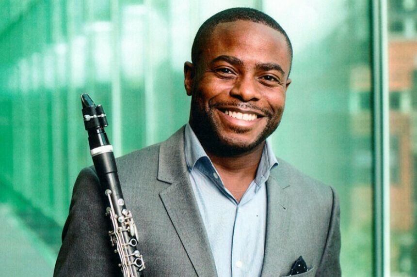 A man holds a clarinet and smiles for the camera.