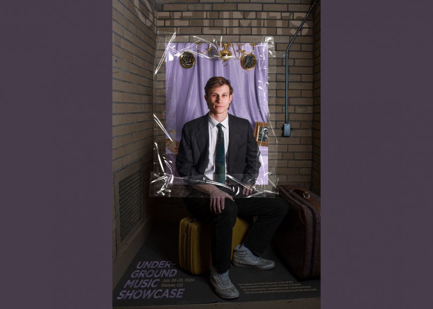 A poster of a man sitting on a crate facing the camera with the words "Off Limits" spray-painted in white on the brick wall behind him.