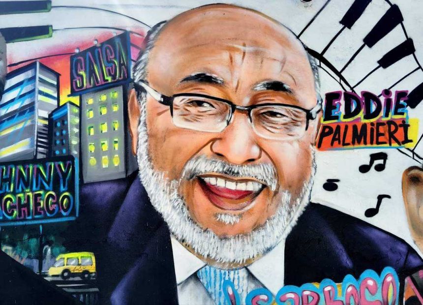 A spray-painted wall mural depicts Latin jazz musician Eddie Palmieri in bold colors.