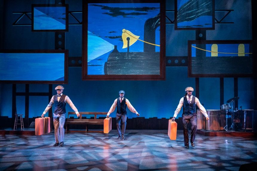 Three Black dancers each carry a suitcase as they step in unison.