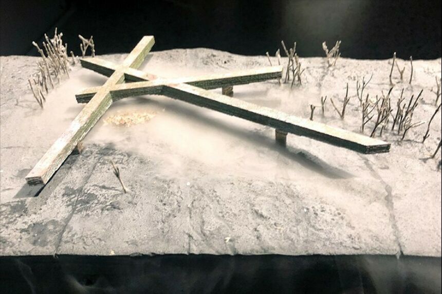 A close up of the Scorched Earth model with a cross on the ground and smoke rising from below