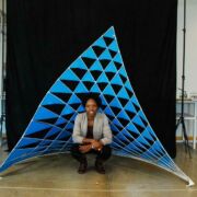 Photo of Vernelle A. A. Noel crouched in front of her self-constructed blue dancing sail sculpture