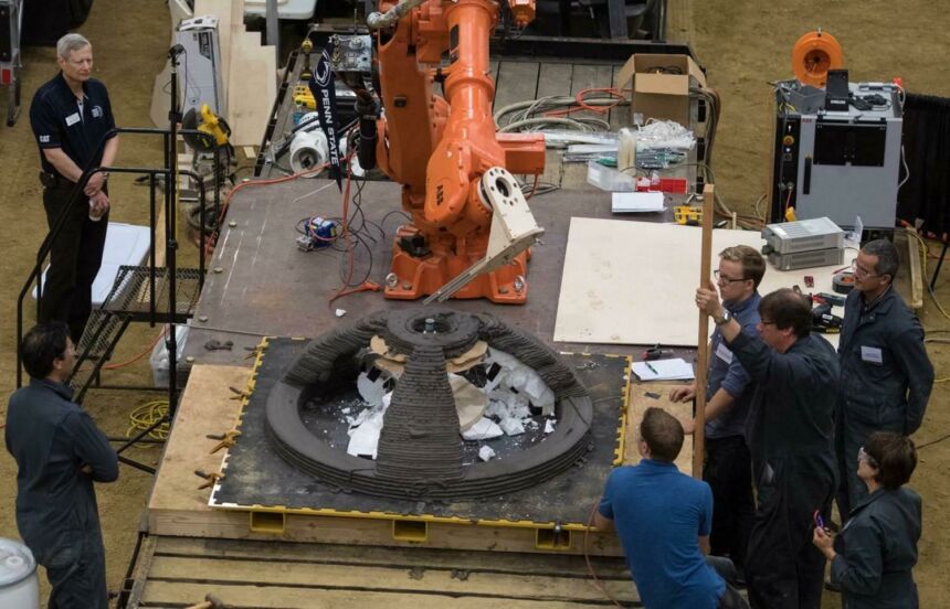Overhead view of Penn State NASA team watching as robot arm prints concrete dome structure