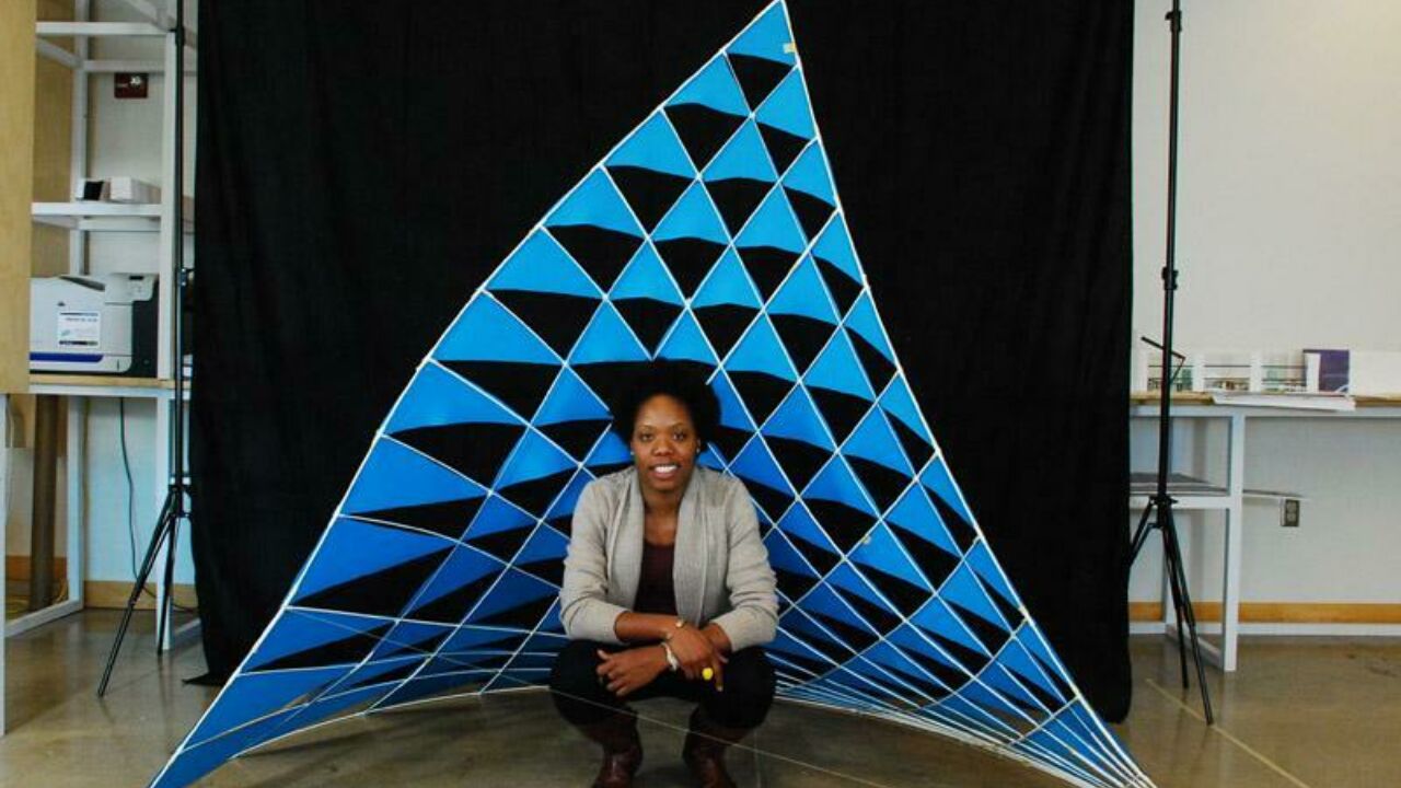 Photo of Vernelle A. A. Noel crouched in front of her self-constructed blue dancing sail sculpture