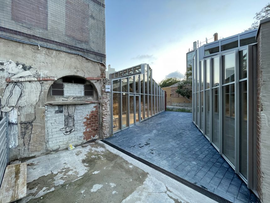 An architectural rendering of a glassed in patio with a crumbling building to the left.