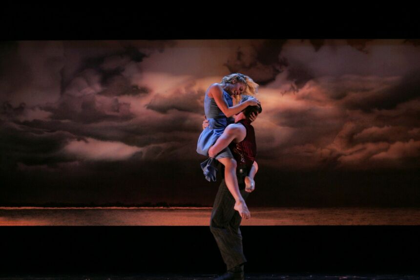 Production still of "Carousel" actors embracing one another on stage.