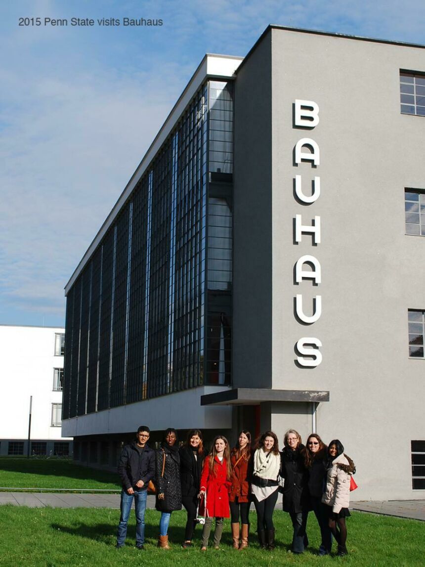 Group photo of Ute with her students standing outside the light grey Bauhaus building during the day.