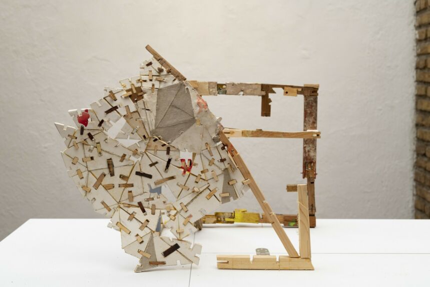 Abstract mixed media structure consisting of dowels and fragmented pieces of wood.