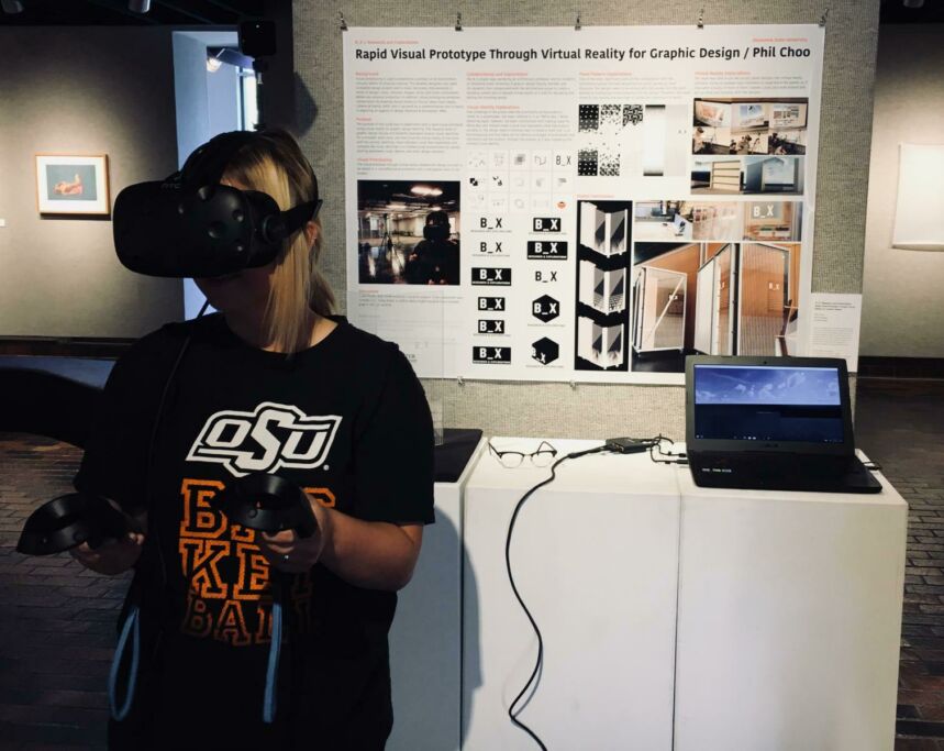 Photo of young woman in black shirt trying out an augmented/virtual reality demo at a booth.