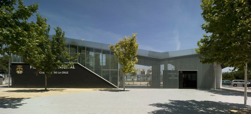 Outdoor view of a pool building with trees obscuring the name of the pool.