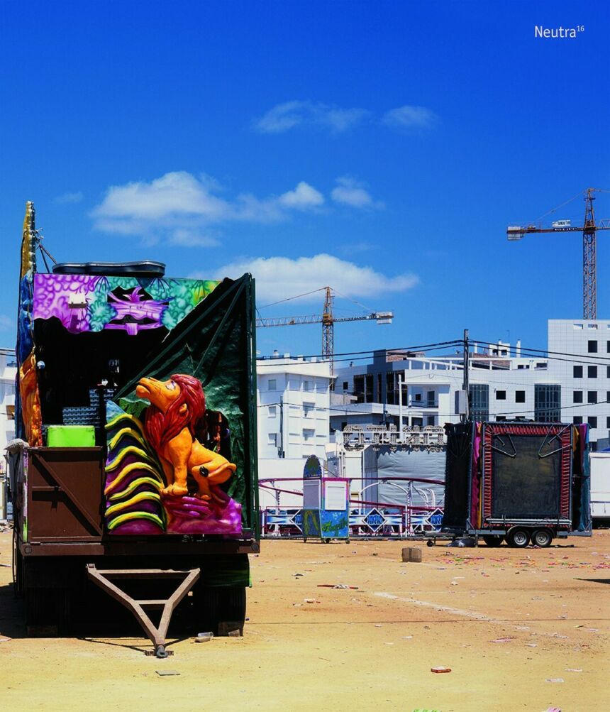 A blue sky behind a shipping dock with an open trailer of colorful circus props.