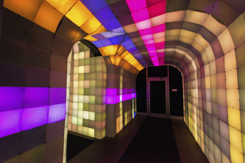 Light box arched hallway of brown, tan, orange, blue, purple, pink, red, and yellow light boxes.