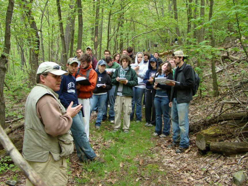 Group photo of Charles Cole lecturing his students in the middle of a forested area.