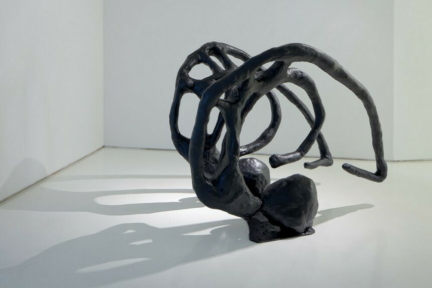 Black abstract sculpture sitting in white room.