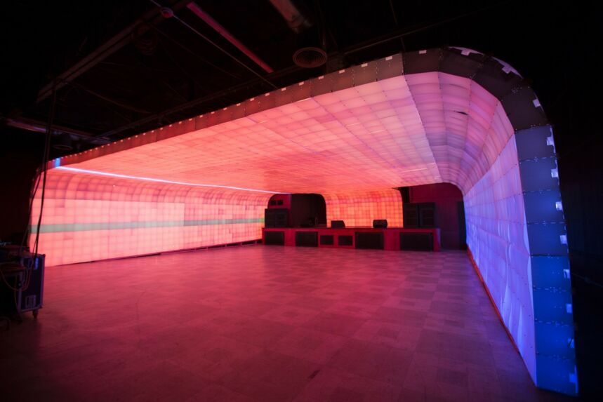 Interior shot of extra wide archway comprised of ombre red, pink, and purple light boxes.