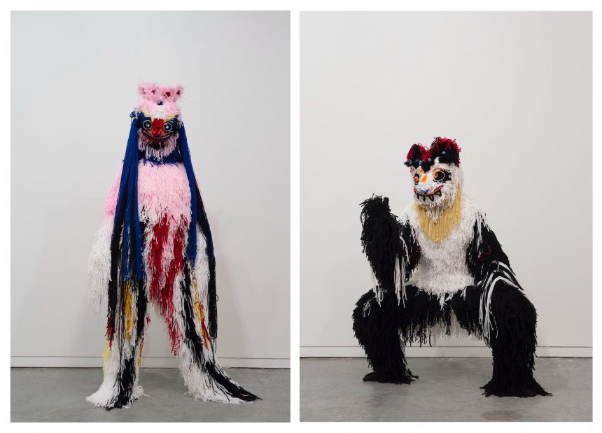 Two human-like feathered costumes, one in an upright pose, one in a crouched pose