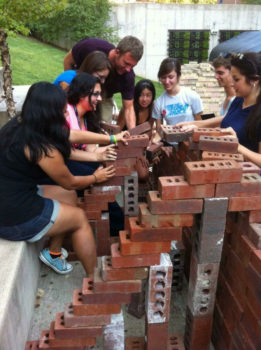 Photo of a team of students working together to build a brick structure.