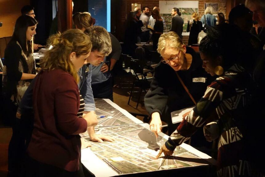 A group of diverse individuals collaborating over printed Google Street maps in an ambient-lit room..