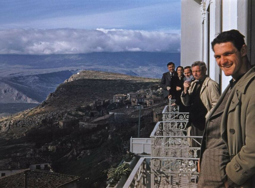 Photo of Kahn and his colleagues on a balcony overlooking a town in a mountainous region, with a thick cloud layer off in the horizon.