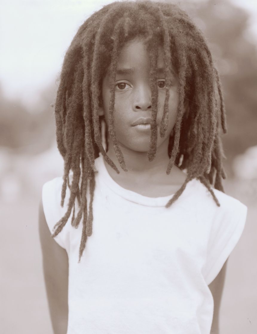 Young child looking through dreadlocks.