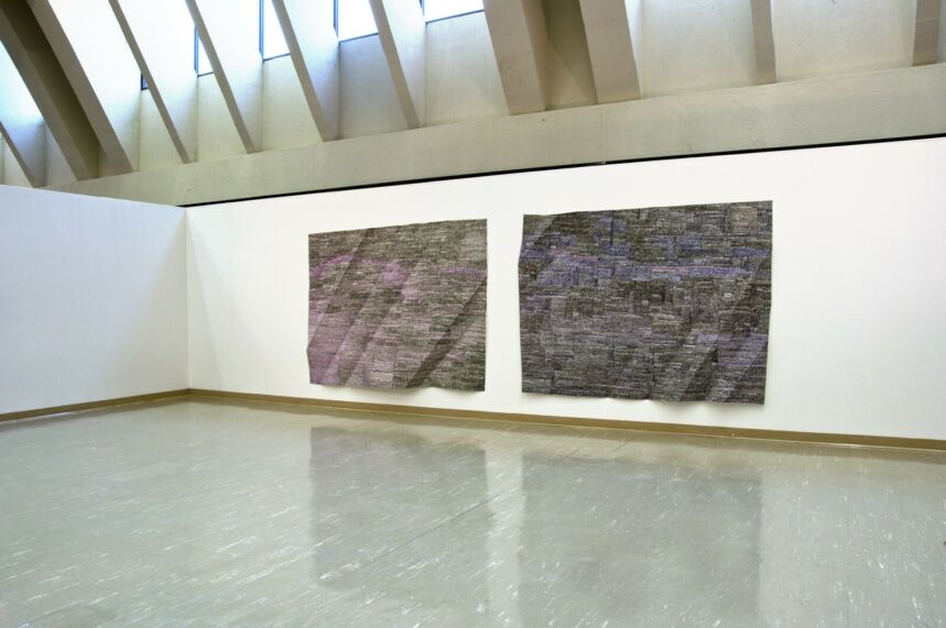 Photo of two large scale paintings on folded paper hanging in a gallery.