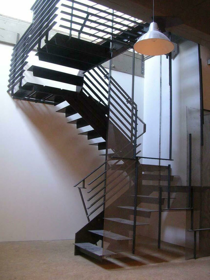 Interior photo of a black metal staircase framed by clear glass paneling.