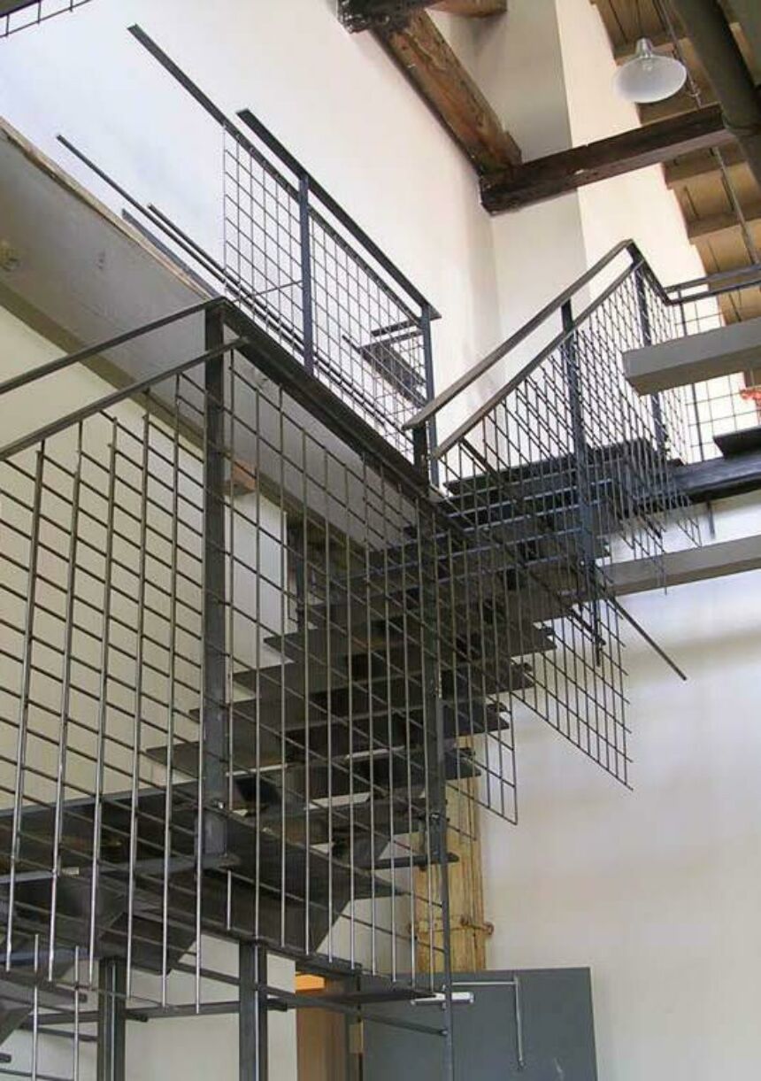 Interior photo of a black metal staircase with a grid-like bannister.