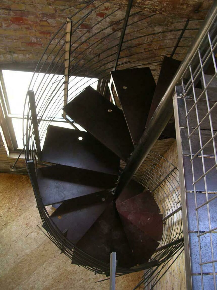 Interior overhead photo of a spiral staircase with dark wood steps and metal cable bannisters.