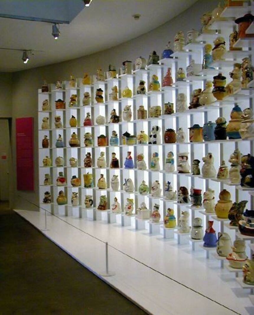 Tall, white curved shelving displaying a wide variety of Andy Warhol's personal cookie jar collection.