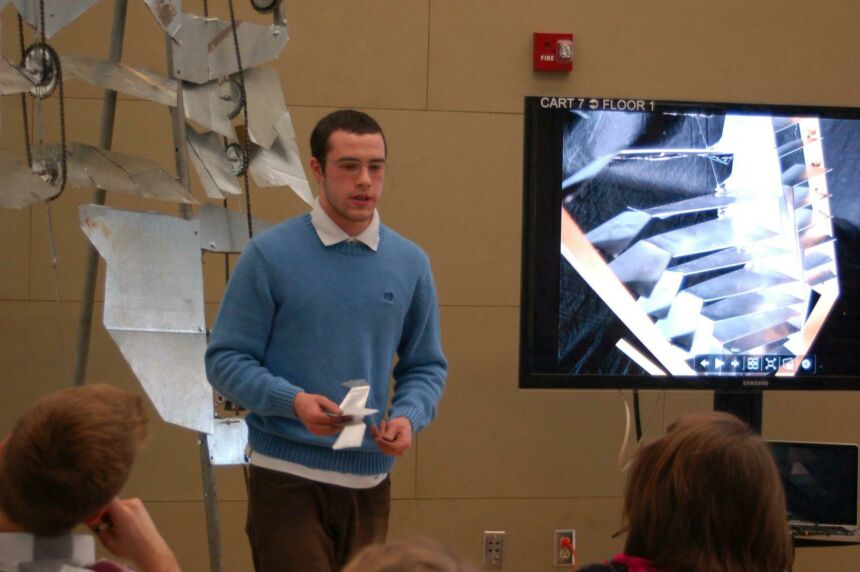 Photo of a male student giving a presentation in front of his class.