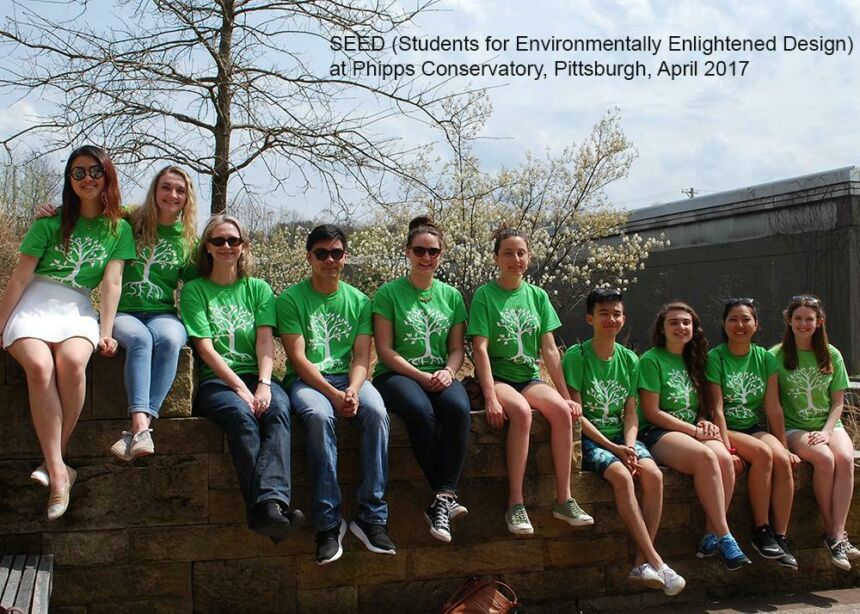 Photo of Ute and her students wearing bright green t-shirts, sitting on a stone wall.
