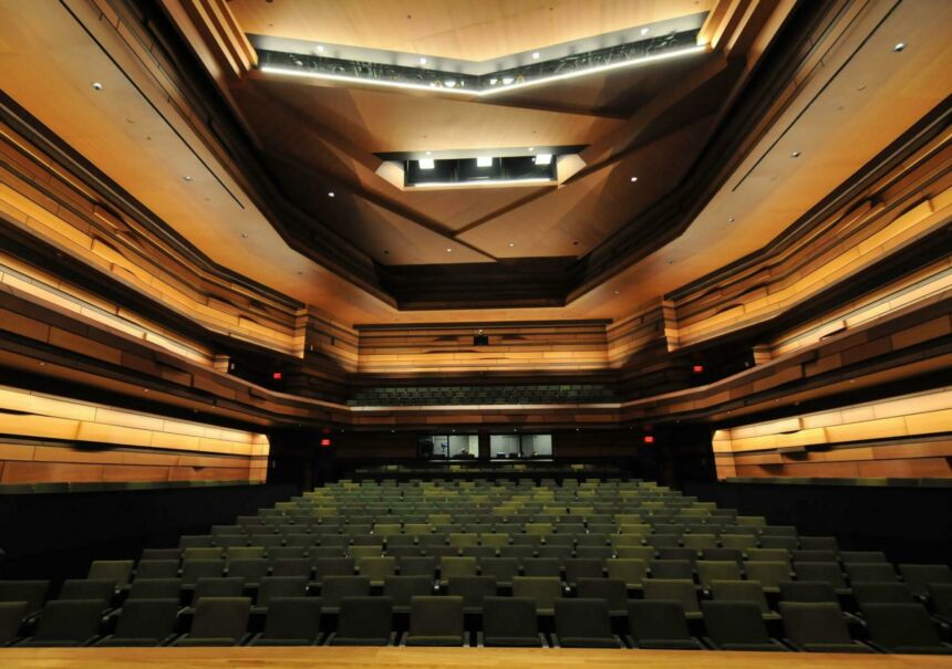 Interior design of a modern-style performance hall's rows of green seats from stage view.